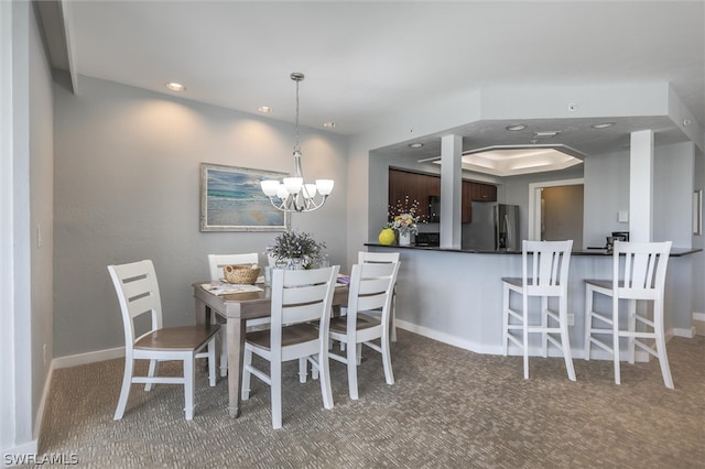 dining area featuring a notable chandelier, carpet, and a raised ceiling