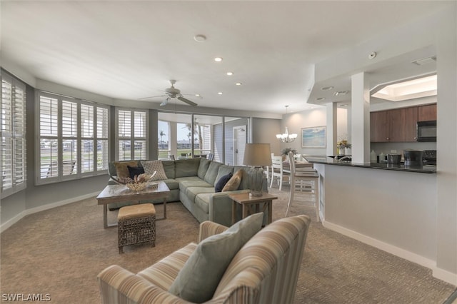 carpeted living room featuring ceiling fan with notable chandelier