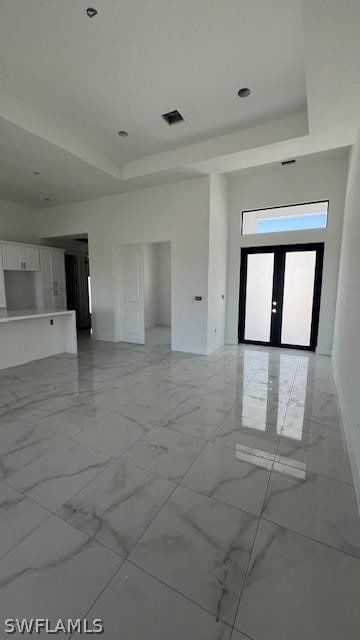 tiled spare room with french doors and a raised ceiling