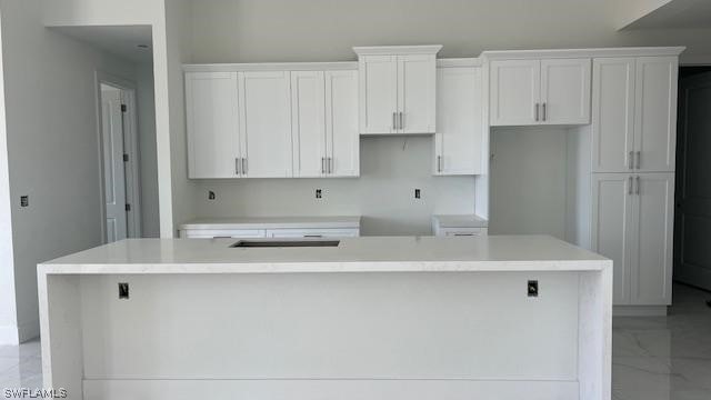 kitchen featuring a kitchen island, white cabinets, and light tile floors