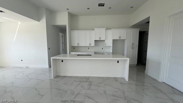 kitchen with white cabinets, a center island, and light tile flooring