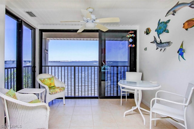 sunroom featuring ceiling fan and a water view