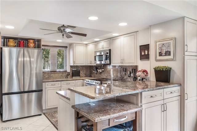 kitchen with appliances with stainless steel finishes, tasteful backsplash, light stone countertops, ceiling fan, and light tile flooring