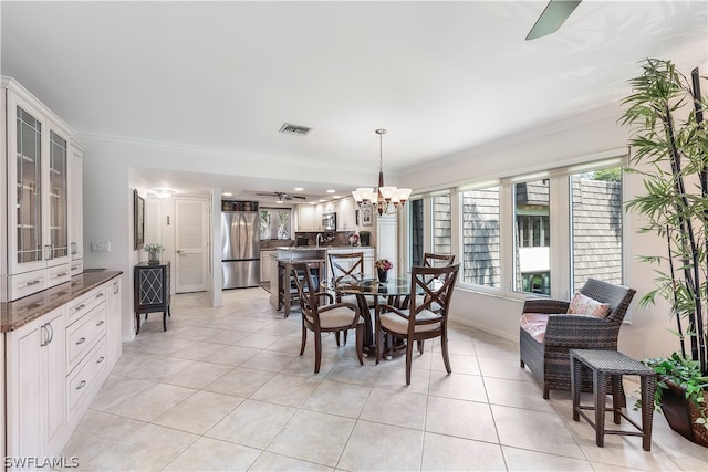 dining room featuring light tile floors, ornamental molding, and ceiling fan with notable chandelier