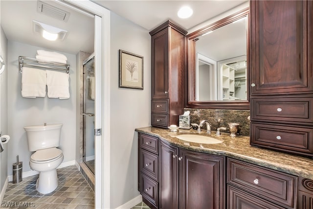 bathroom featuring tile flooring, toilet, vanity, and a shower with door