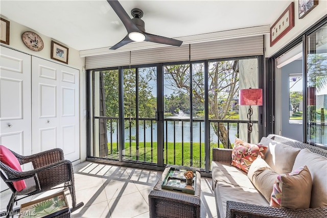 sunroom / solarium with ceiling fan and a water view