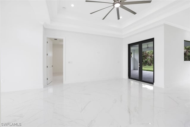 tiled empty room featuring ceiling fan, french doors, a tray ceiling, and ornamental molding