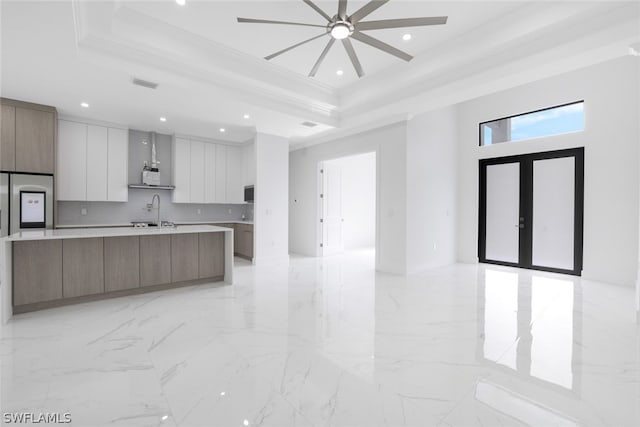 kitchen with crown molding, light tile patterned floors, ceiling fan, a raised ceiling, and a spacious island