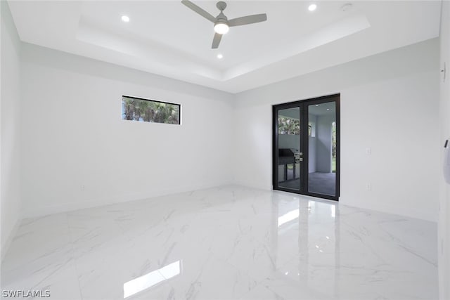 spare room featuring ceiling fan, tile patterned flooring, french doors, and a tray ceiling