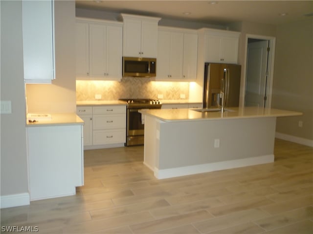 kitchen featuring tasteful backsplash, white cabinets, a kitchen island, stainless steel appliances, and light hardwood / wood-style flooring