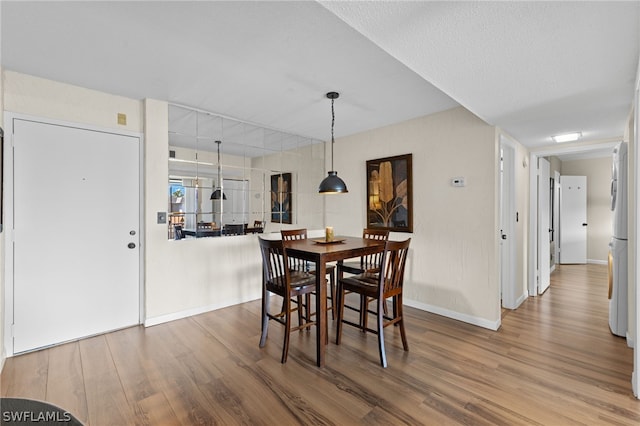 dining space with wood-type flooring and a textured ceiling