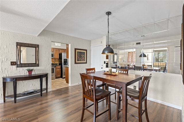 dining space featuring dark hardwood / wood-style flooring and a textured ceiling