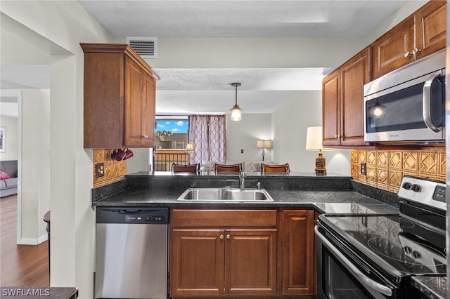 kitchen with decorative backsplash, dark hardwood / wood-style flooring, a textured ceiling, stainless steel appliances, and sink