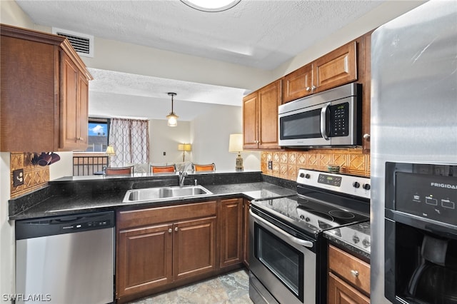 kitchen with appliances with stainless steel finishes, tasteful backsplash, a textured ceiling, sink, and dark stone countertops