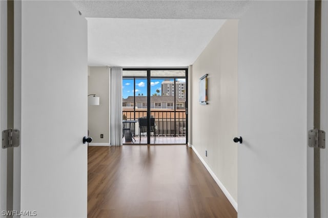 unfurnished room featuring expansive windows, a textured ceiling, and dark wood-type flooring