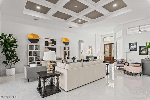 living room with a high ceiling, coffered ceiling, french doors, ceiling fan, and beamed ceiling