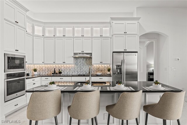 kitchen featuring a kitchen breakfast bar, stainless steel appliances, sink, a center island with sink, and white cabinets