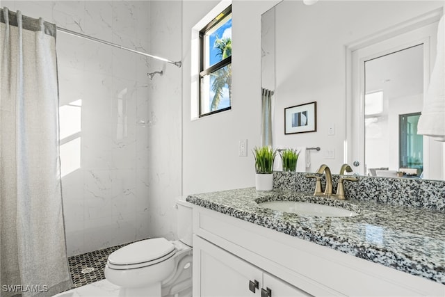 bathroom with tiled shower, vanity, and toilet