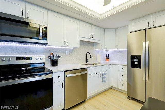 kitchen with ornamental molding, appliances with stainless steel finishes, white cabinetry, and sink