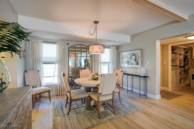 dining area with beam ceiling, a healthy amount of sunlight, and light hardwood / wood-style flooring