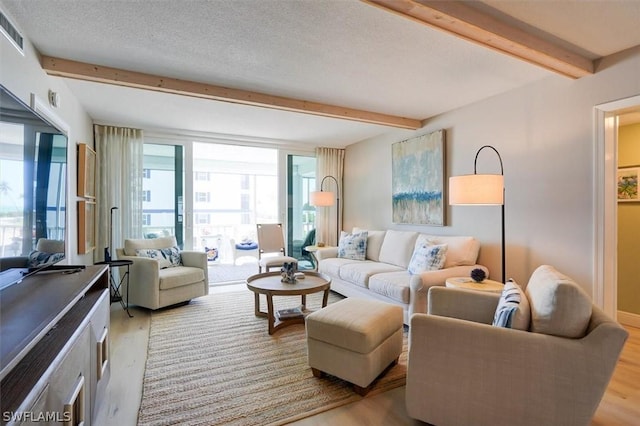 living room featuring a textured ceiling, light hardwood / wood-style floors, and beamed ceiling