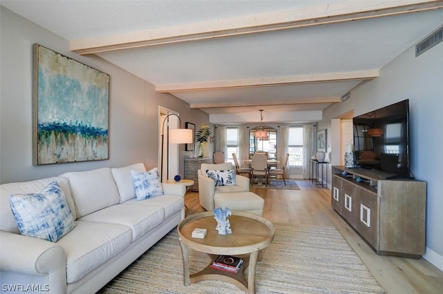 living room with light hardwood / wood-style floors and beamed ceiling