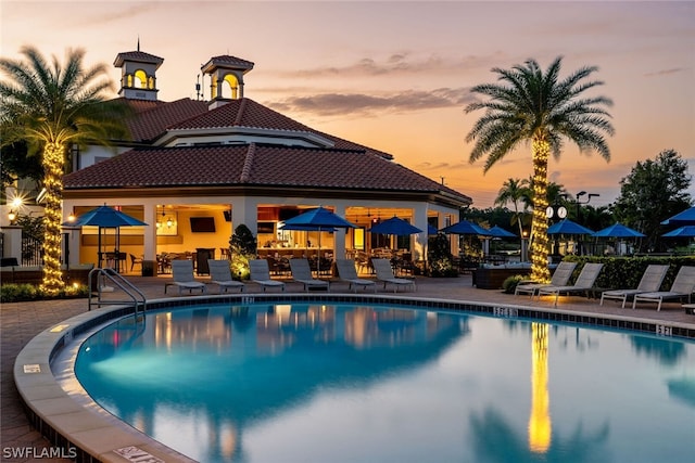 pool at dusk with a patio area