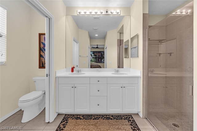 bathroom featuring a shower with door, tile flooring, double vanity, and toilet