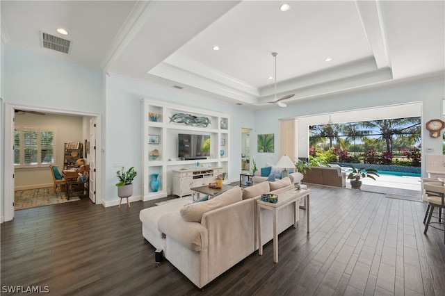 living room featuring ceiling fan, a raised ceiling, dark hardwood / wood-style flooring, and ornamental molding