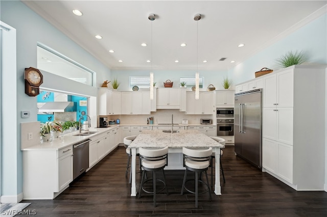 kitchen featuring built in appliances, dark wood-type flooring, white cabinets, and decorative light fixtures