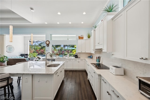 kitchen featuring light stone countertops, a kitchen bar, hanging light fixtures, dark hardwood / wood-style floors, and sink