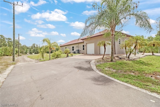 view of front of home with a garage and central air condition unit