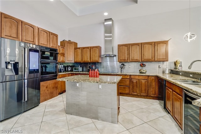 kitchen featuring hanging light fixtures, black appliances, backsplash, wall chimney range hood, and light stone counters