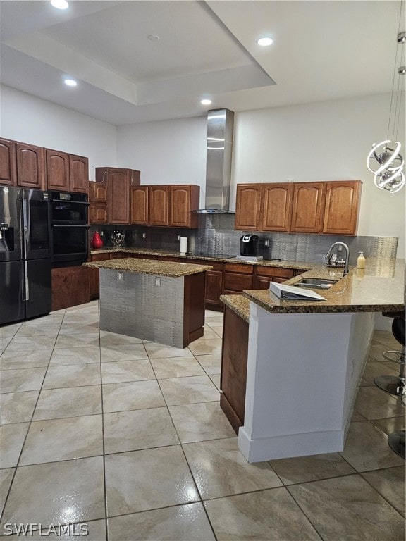 kitchen featuring wall chimney exhaust hood, hanging light fixtures, black fridge, sink, and tasteful backsplash