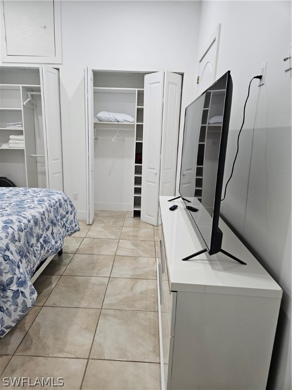 bedroom with ceiling fan, two closets, and light tile flooring