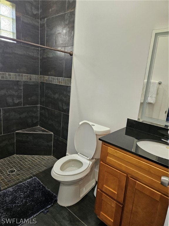 bathroom with toilet, vanity, and a tile shower