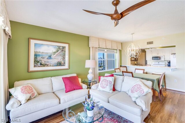 living room featuring hardwood / wood-style floors and ceiling fan with notable chandelier