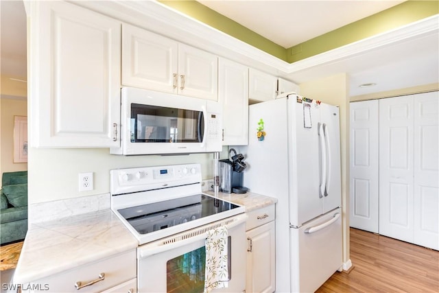 kitchen with white cabinetry, light hardwood / wood-style flooring, and white appliances