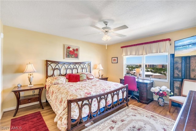 bedroom with ceiling fan, light hardwood / wood-style floors, and a textured ceiling