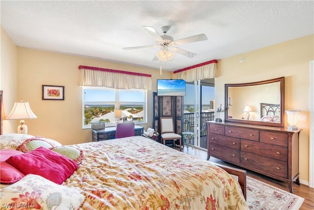 bedroom with access to exterior, a textured ceiling, hardwood / wood-style flooring, and ceiling fan