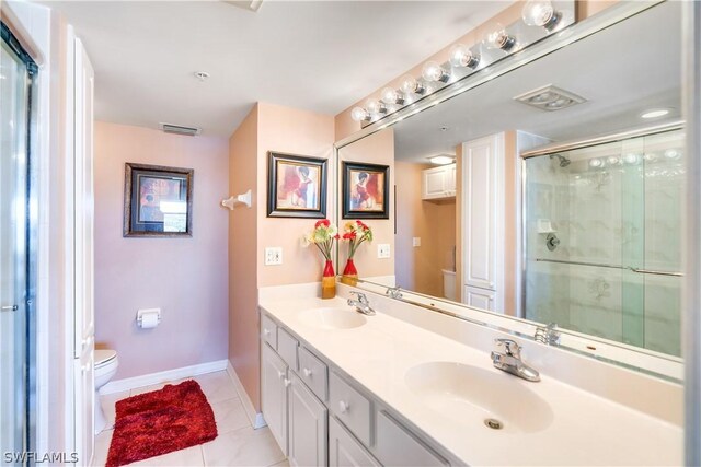 bathroom with tile patterned flooring, vanity, toilet, and a shower with door