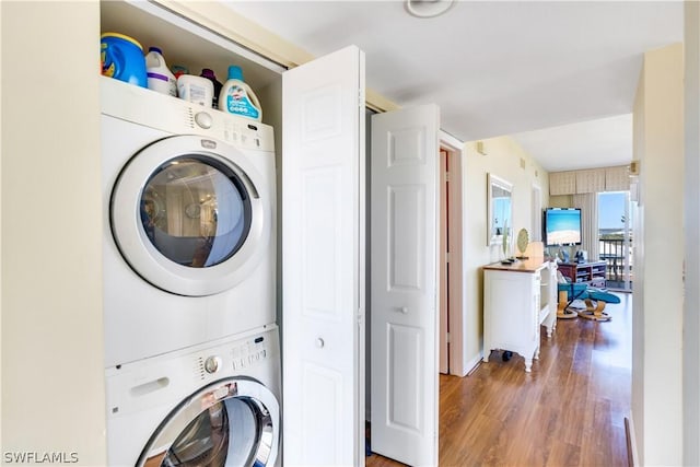 laundry area with stacked washer and dryer and hardwood / wood-style flooring