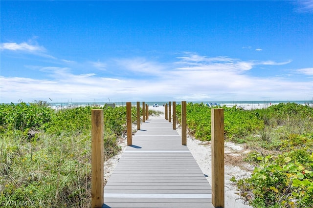 view of dock with a beach view and a water view