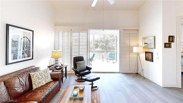 living room featuring wood finished floors, a ceiling fan, and baseboards