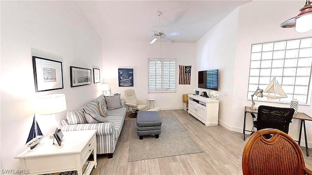 living room featuring light wood-type flooring, ceiling fan, baseboards, and lofted ceiling