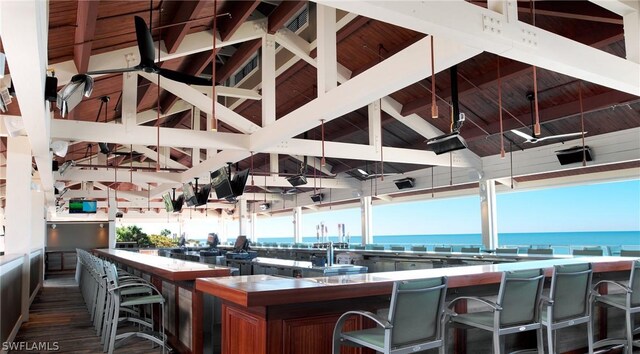 interior space featuring wood ceiling, a breakfast bar area, lofted ceiling with beams, and a water view