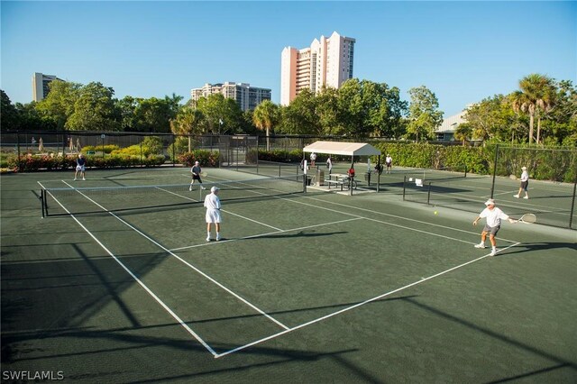 view of tennis court featuring a view of city and fence