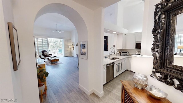 kitchen with sink, light hardwood / wood-style flooring, stainless steel dishwasher, ceiling fan, and white cabinets