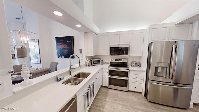 kitchen with appliances with stainless steel finishes, light countertops, white cabinetry, pendant lighting, and a sink