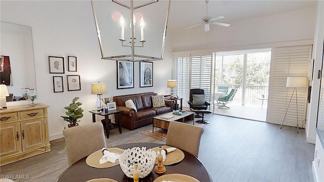 living area featuring light wood-type flooring and ceiling fan with notable chandelier